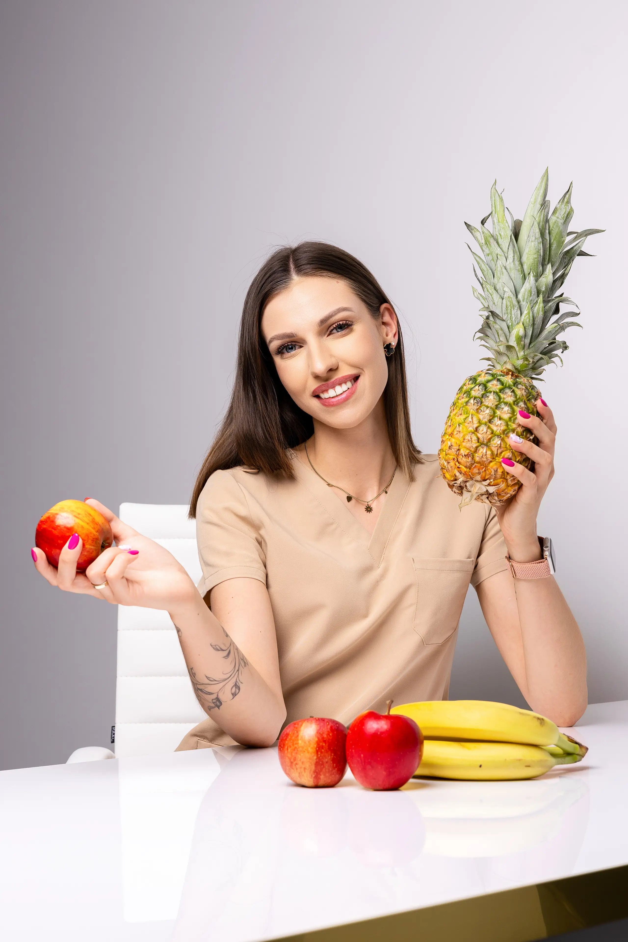 Paulina Janik, dietetyk, przy biurku z ananasem i jabłkiem